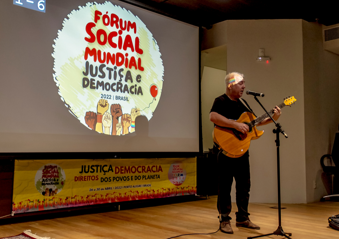 Homem tocando violão e cantando no palco do Fórum Social Mundial
