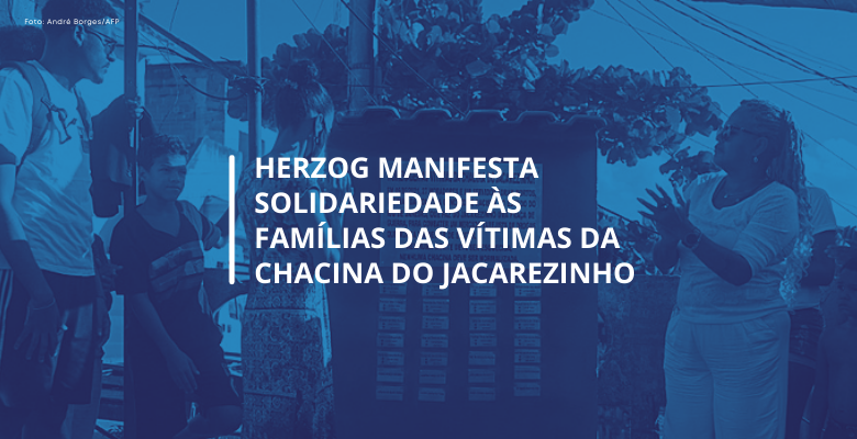 Fotografia com filtro azulado da inauguração de Memorial em homenagem às vítimas da chacina do Jacarezinho. O texto diz "Herzog manifesta solidariedade às famílias das vítimas da chacina do Jacarezinho"