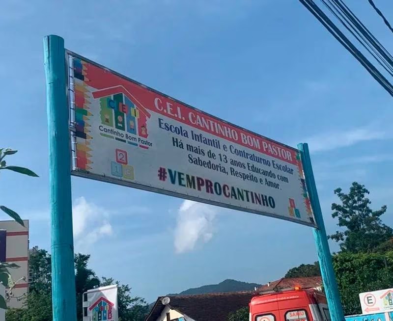 Fotografia colorida de placa de identificação da Creche Cantinho Bom Pastor, escola infantil alvo de um ataque que vitimou 4 crianças